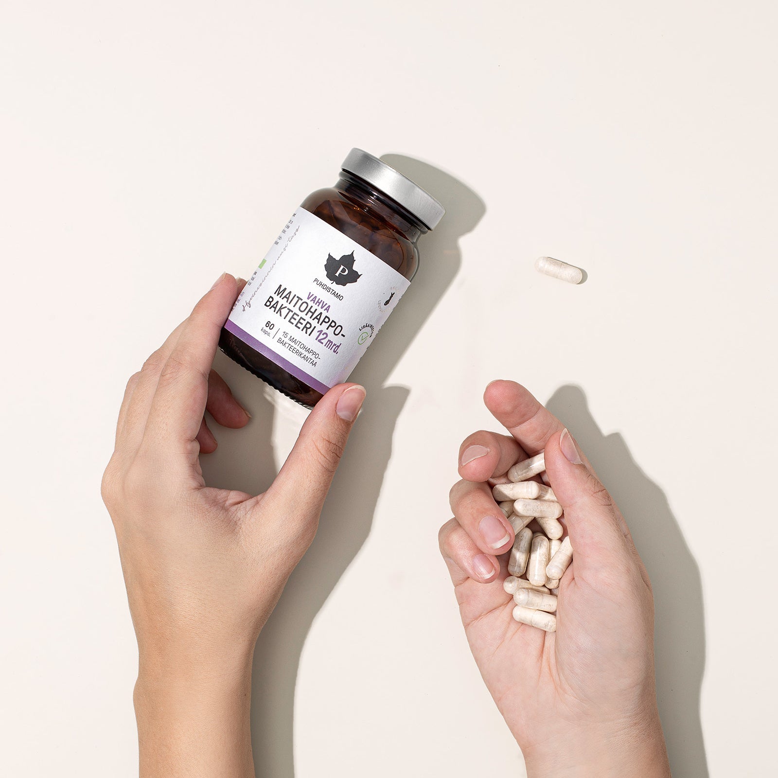 Two hands holding a supplement bottle and capsules.