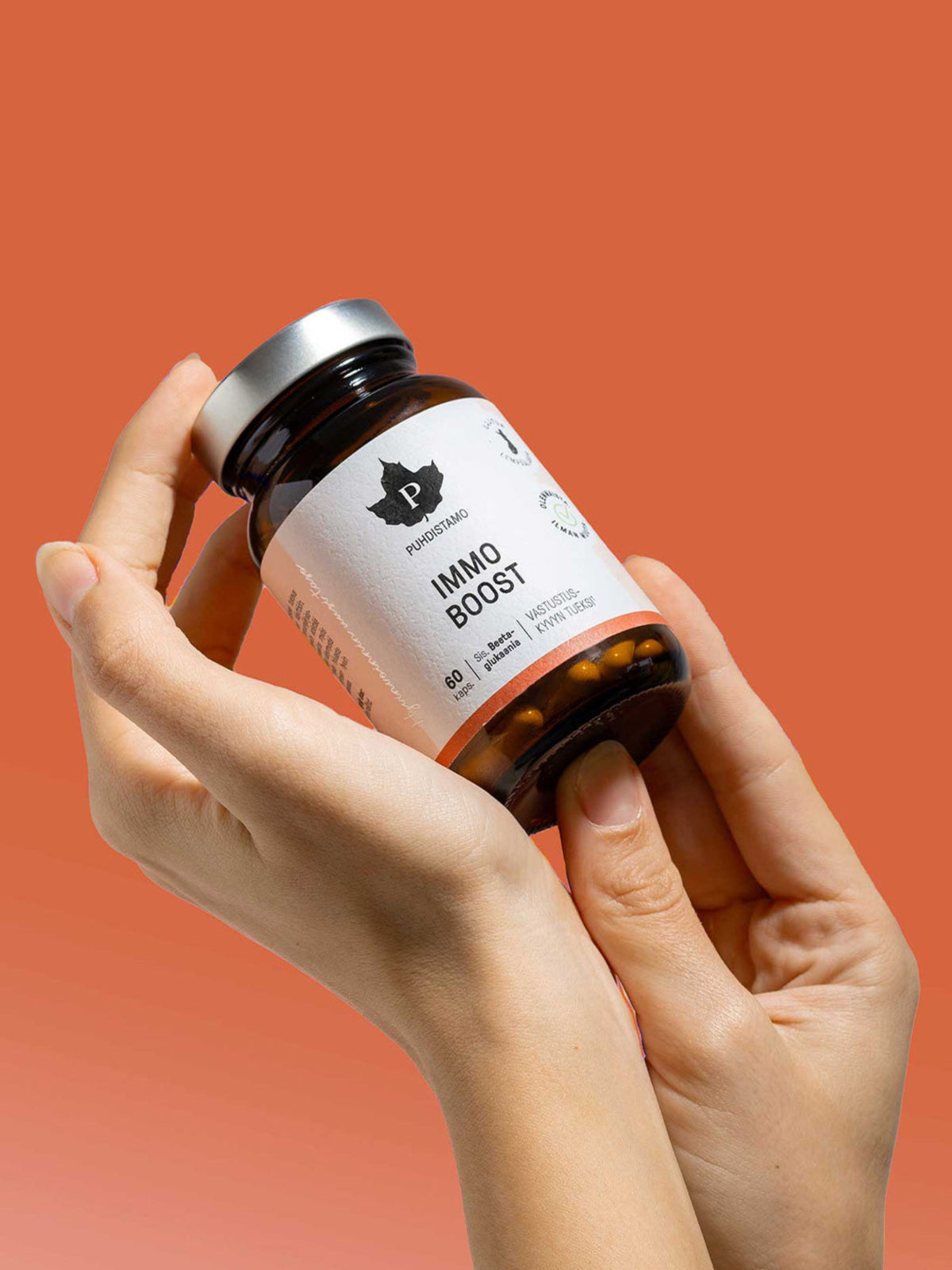 Nainen pitelee käsissään Puhdistamon Immo Boost 60 kapselin purkkia