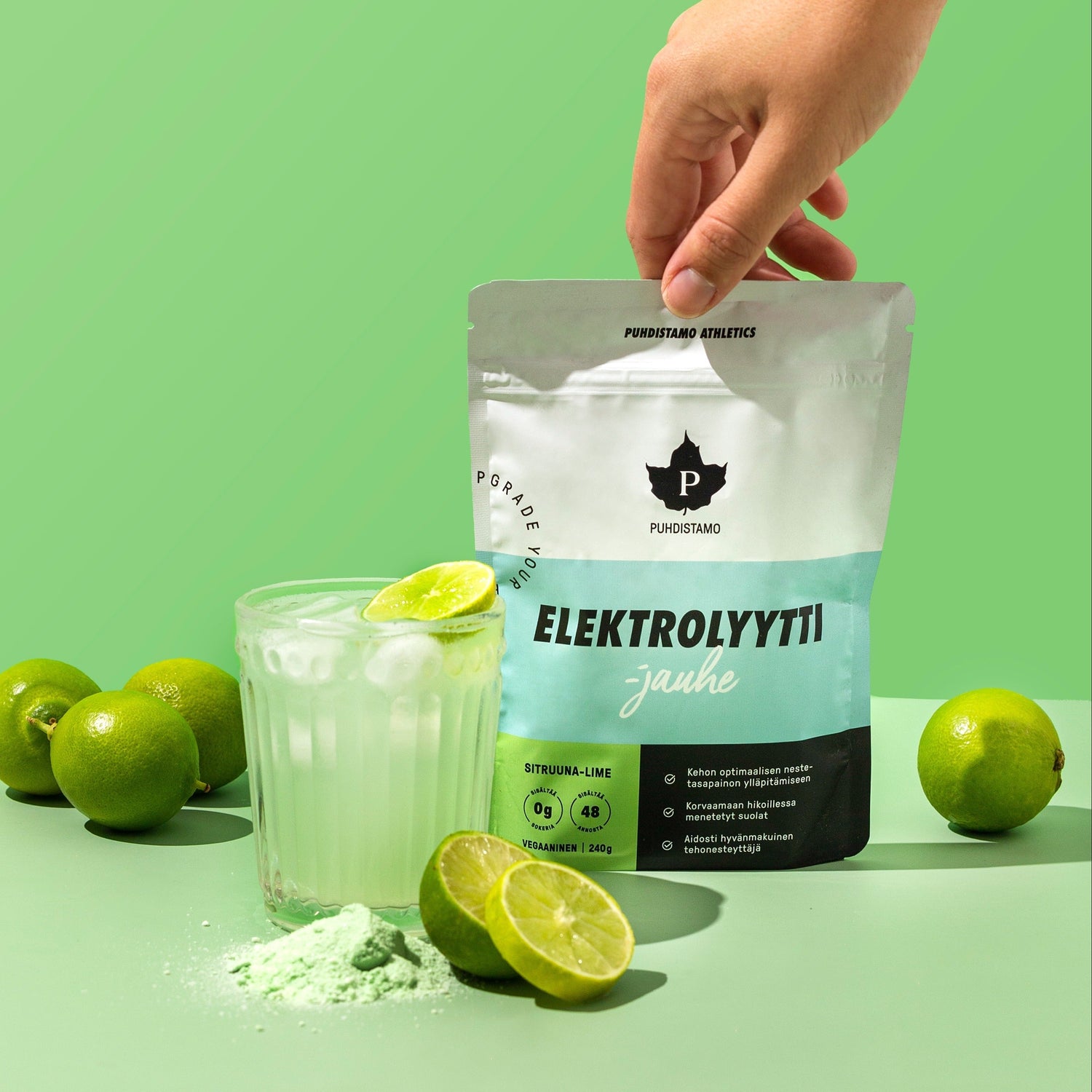Hand holding electrolyte powder bag next to a drink and limes.