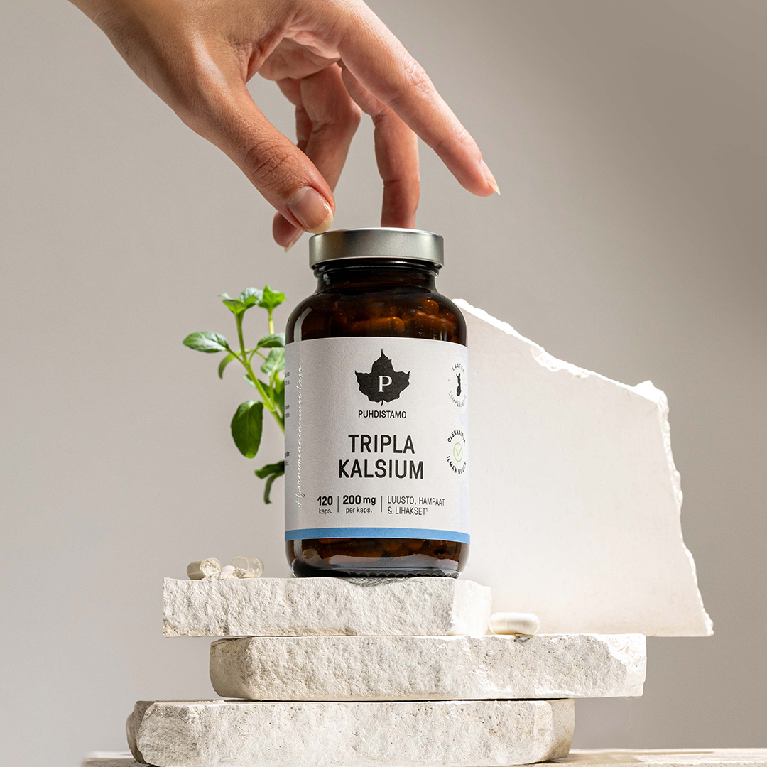 Hand reaching for a bottle of Tripla Kalsium on stone blocks.