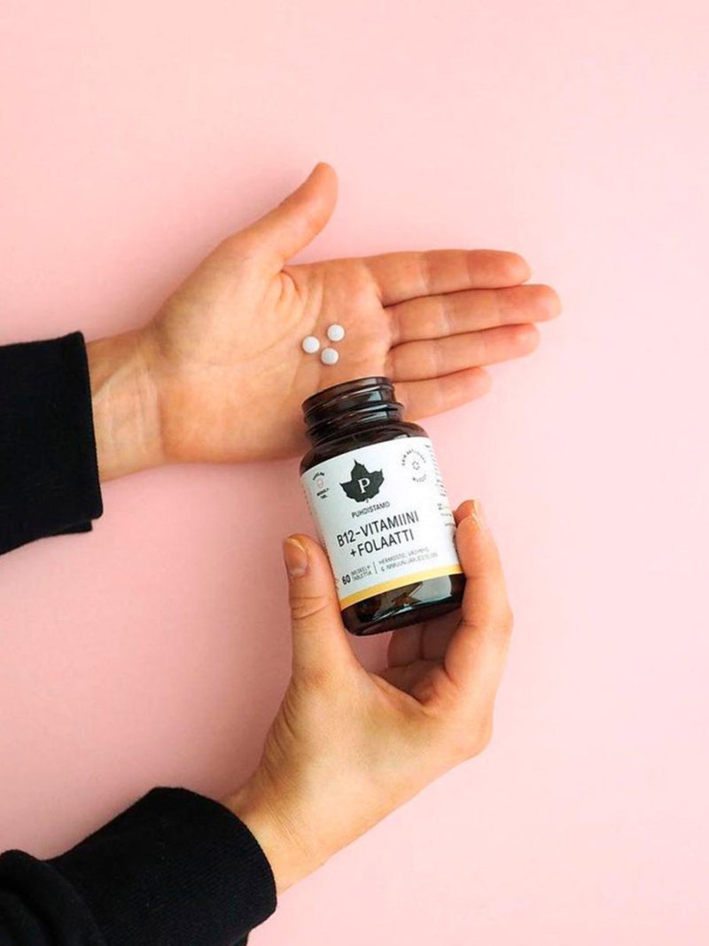 B12-vitamiini + Folaatti imeskelytabletit kädessä
