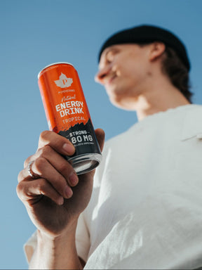 Mies pitää kädessään Puhdistamon Natural Energy Drink Tropical Strong tölkkiä