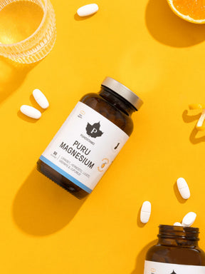 Puhdistamon Puru Magnesium purkki ja kapseleita oranssia taustaa vasten