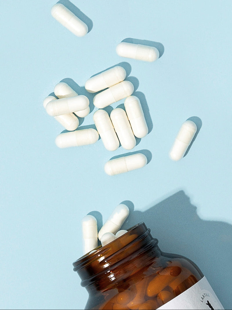 Puhdistamon Tripla Magnesium purkki ja kapseleita vaaleansinistä taustaa vasten