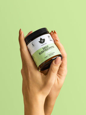 Nainen pitelee käsissään Puhdistamon Daily Elektrolyyttijauhe Lime -purkkia