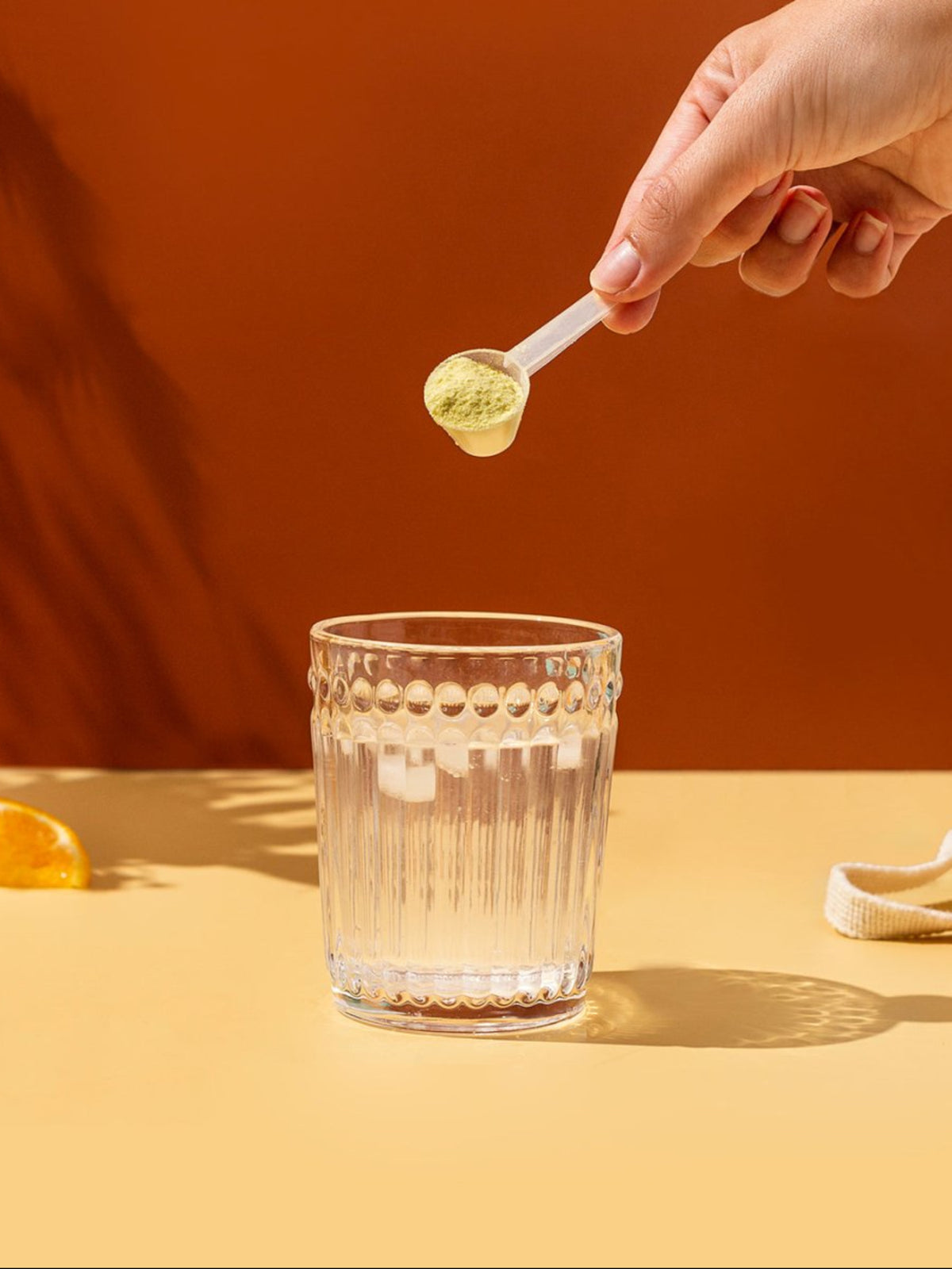 Nainen kaataa vesilasiin Elektrolyyttijauhetta Mango-appelsiini