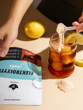 Nainen kaataa vesilasiin Puhdistamon Elektrolyyttijauhetta Sitruuna-Cola