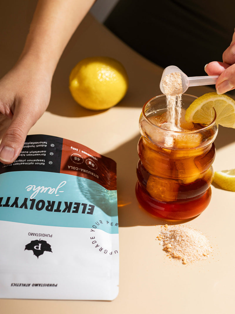 Nainen kaataa vesilasiin Puhdistamon Elektrolyyttijauhetta Sitruuna-Cola