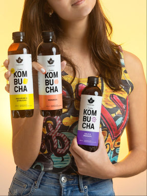 Nainen pitää käsissään Puhdistamon Luomu Kombucha pulloja