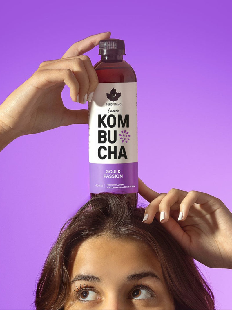 Nainen pitää päänsä päällä Puhdistamon Luomu Kombucha Goji-passion pulloa