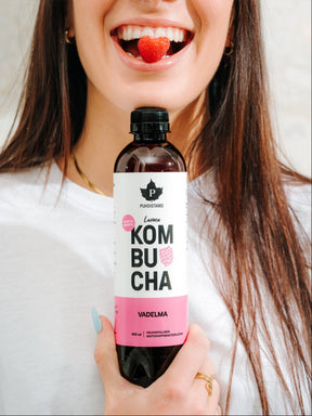 Nainen pitää kädessään Puhdistamon Luomu Kombucha vadelma pulloa