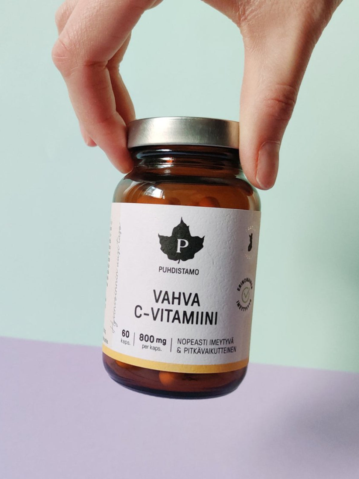 Nainen pitää kädessään Puhdistamon Vahva C-vitamiini purkkia